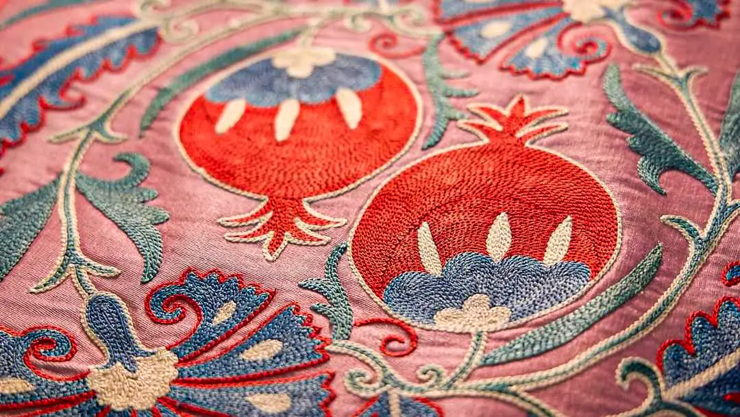 Изображение двух гранатов в технике ручной вышивки на текстиле.