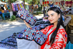 Молодая узбечка держит тюбетейки на узбекской ярмарке.